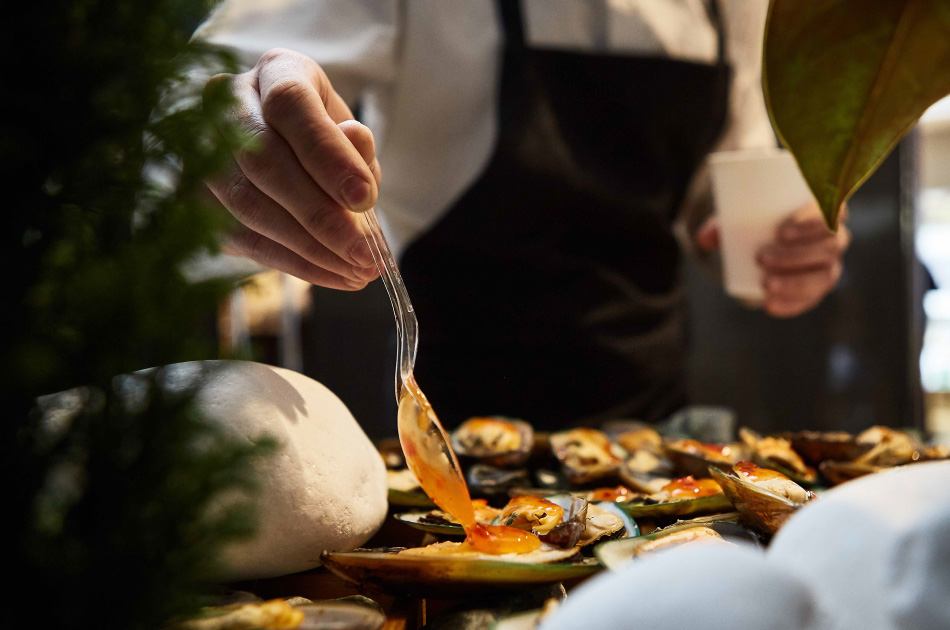 close-up of chef spooning sauce on tray of appetizers close-up of chef spooning sauce on tray of appetizers